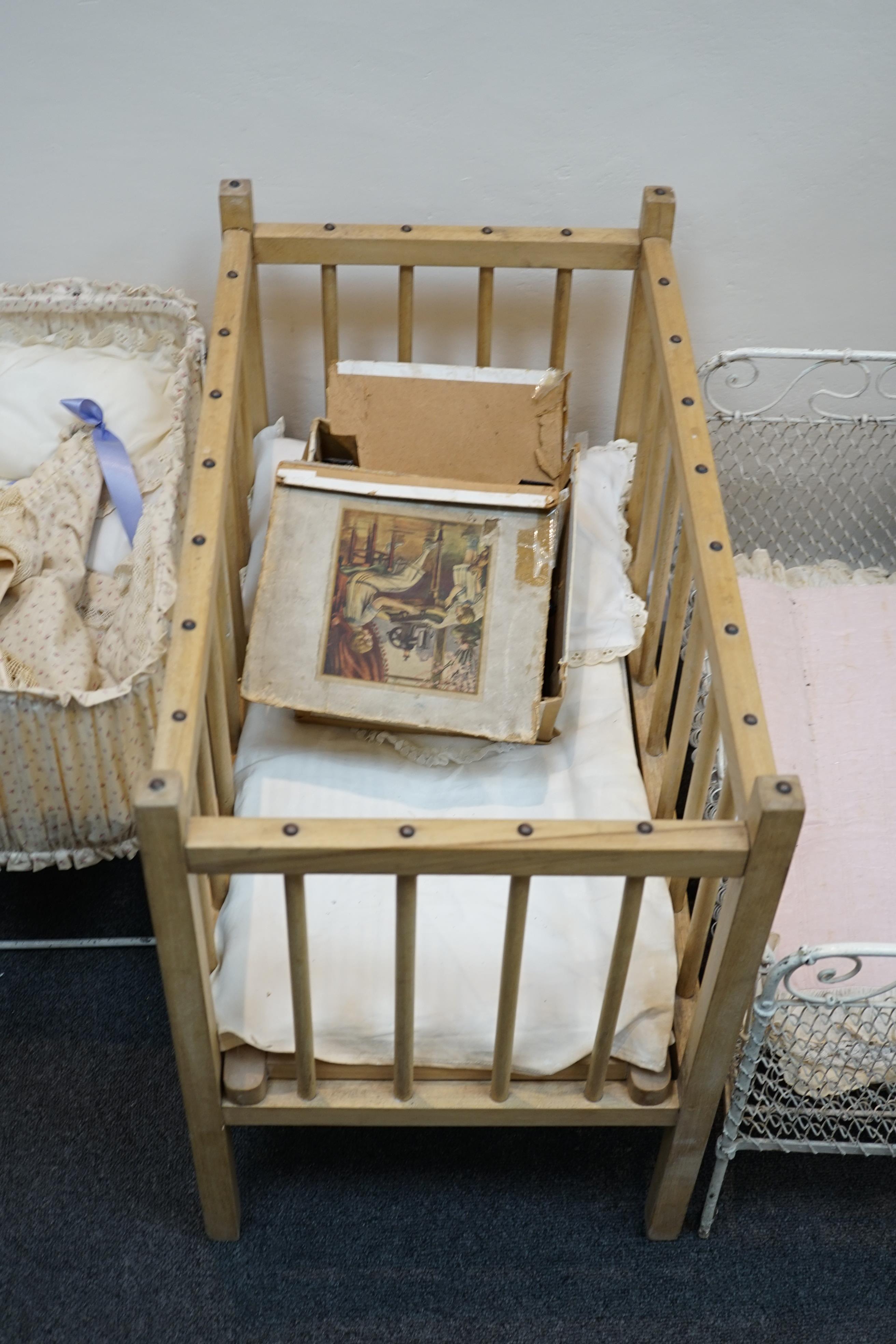 A collection of nine doll’s cribs of wood or wrought iron construction, together with two nineteenth century style doll’s ’bath chairs’, a toy mangle, Disney themed Snow White carpet sweeper and a boxed child’s sewing ma